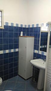アルカモにあるFiori d'Ulivo Casa Vacanzaの青いタイル張りのバスルーム(洗面台、トイレ付)