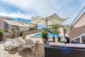 Un patio con sillas y sombrillas y una piscina. en Apartments Nika & Karla, en Bibinje