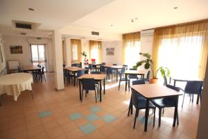 una sala da pranzo con tavoli, sedie e finestre di Hotel San Nazario a Varazze