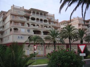 a large building with palm trees in front of it at Almerimar Apartment in Almerimar