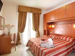 ein Hotelzimmer mit einem Bett und einem Tisch mit Blumen darauf in der Unterkunft Hotel Storione in Lido di Jesolo