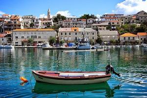 ein Boot im Wasser mit einer Stadt im Hintergrund in der Unterkunft Apartment Antica in Povlja