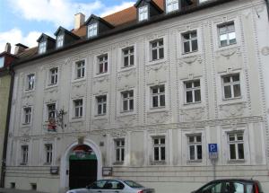 ein weißes Gebäude mit einer Tür und vor der Tür geparkt in der Unterkunft KulturQuartier in Regensburg