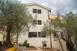 a white house with trees in front of it at Apartmani Ksenija in Petrovac na Moru