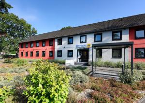 a red and white building with plants in front of it at Best Deal Airporthotel Weeze in Weeze