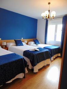 drie bedden in een kamer met blauwe muren bij El Rincón de Antonio in Casarrubios del Monte