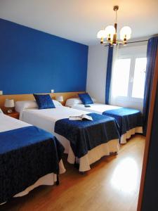 Tres camas en una habitación con paredes azules. en El Rincón de Antonio, en Casarrubios del Monte