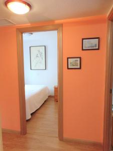 Un dormitorio con una pared de color naranja y una cama en El Rincón de Antonio, en Casarrubios del Monte