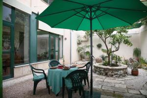 a table and chairs with a green umbrella at Casa Familiar y Acogedora in Sa Pobla
