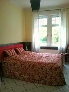 a bedroom with a bed with a red comforter and a window at Ferienwohnung Mosel-Rhein in Koblenz