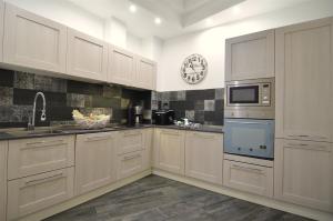 a kitchen with white cabinets and a clock on the wall at Appartamento fronte mare in Moneglia