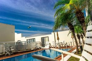 聖保羅的住宿－特蘇宮公寓酒店，一座游泳池,旁边是椅子和棕榈树