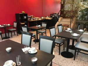 a restaurant with tables and chairs and a red wall at Hotel De L'Europe in Toul