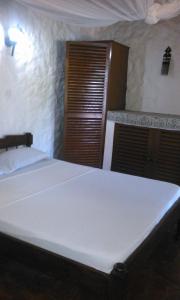 um quarto com uma cama branca e uma porta de madeira em Diani Banda Cottages em Diani Beach