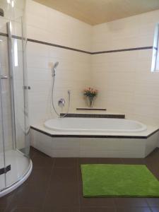 ein Badezimmer mit einer Badewanne mit einer Dusche und einem grünen Teppich in der Unterkunft Haus Seehof - Ferienhaus in Abersee