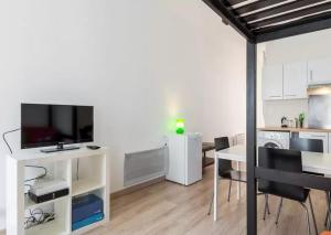 a living room with a table with a tv and a kitchen at LyonPaulBert in Lyon