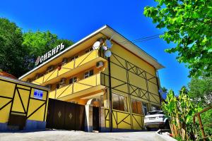 a yellow building with a sign on the side of it at Sibir Mini-hotel in Adler