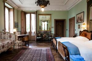 1 dormitorio con 2 camas, sofá y mesa en Villa Cernigliaro Dimora Storica, en Sordevolo