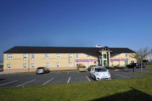 ein großes Gebäude mit Autos auf einem Parkplatz in der Unterkunft Hotel Inn Design Issoudun in Issoudun