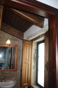 ein Badezimmer mit Waschbecken, Spiegel und Fenster in der Unterkunft A Casa da Meixida in Padrón