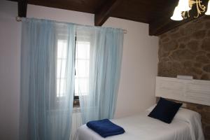 Schlafzimmer mit einem Bett mit blauen Vorhängen und einem Fenster in der Unterkunft A Casa da Meixida in Padrón