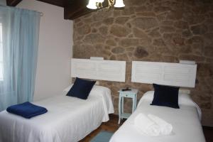 2 Betten in einem Zimmer mit einer Steinmauer in der Unterkunft A Casa da Meixida in Padrón