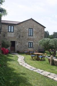 una casa de piedra con mesa y mesas de picnic en A Casa da Meixida, en Padrón