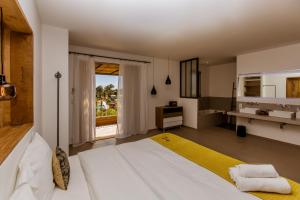 a bedroom with a large white bed and a bathroom at Hotel Les Chambres de Mila Bonifacio in Bonifacio