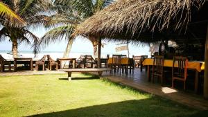 um restaurante com mesas e cadeiras na praia em The Den Guest House em Hikkaduwa