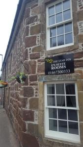 a sign on the side of a brick building with a window at Star Inn Rooms in Ardersier