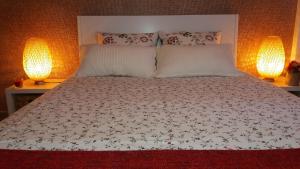 a bedroom with a bed with two lamps on it at Apartamento Praiamar in Vila Nova de Milfontes
