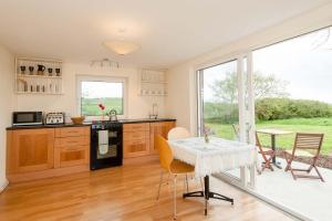 cocina con mesa, sillas y ventana en The Wild Atlantic Hideaway, en Clonakilty