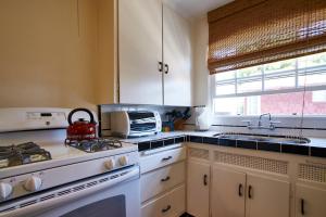 La cocina está equipada con armarios blancos y fogones con tetera. en Arabella Laguna, en Laguna Beach