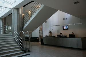 um lobby com duas pessoas sentadas em uma mesa em um edifício em San Diego Apart- Hotel em Belo Horizonte