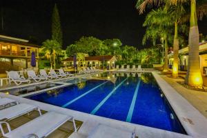 a pool with white lounge chairs and a resort at night at Sun Valley Marília by Atlantica in Marília