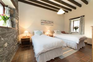 two beds in a room with a stone wall at Conwy Valley Cottages in Conwy