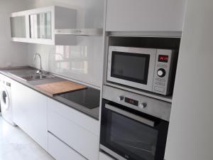 a white kitchen with a microwave and a sink at Apartamento Las 4 Palmeras in Córdoba