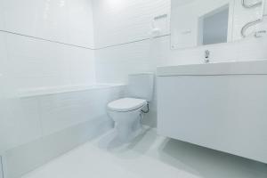 a white bathroom with a toilet and a sink at VIP Apartment ob Gorkogo Square in Sumy
