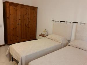 a bedroom with two beds and a wooden cabinet at I Mandorli in Olbia