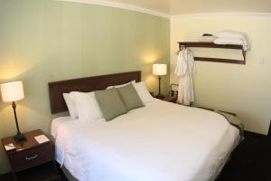 The Mammoth Creek Inn في بحيرات ماموث: غرفة نوم بسرير ابيض كبير ومصباحين