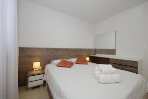 a bedroom with a large white bed with towels on it at Valadar Apartments in Privlaka