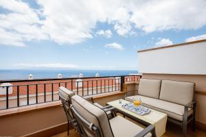 a balcony with two chairs and a table with drinks on it at Residencial Playa de La Arena in Puerto de Santiago