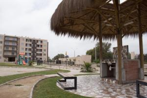 un parque con banco y sombrilla de paja en Condominio Mistral V, en La Serena
