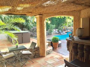 a patio with a table and chairs and a pool at Le Mas d'Olivier in Le Plan-de-la-Tour