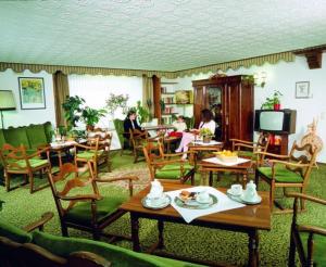 uma sala de estar com mesas e cadeiras e pessoas sentadas em Hotel Traube em Bad Wildbad