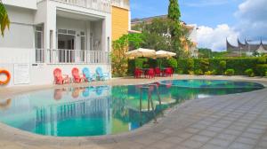 una piscina con sedie rosse e ombrellone di Ibis Padang a Padang