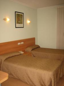 a hotel room with two beds and a table at Hostal Madruga in Elche