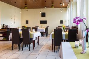 ein Restaurant mit weißen Tischen, Stühlen und lila Blumen in der Unterkunft Hotel Landgasthaus Sockenbacher Hof in Strümpfelbrunn