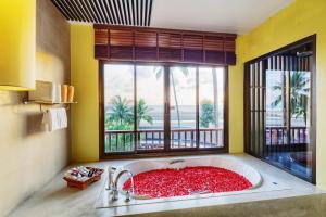 ein Badezimmer mit einer großen Badewanne und einem Fenster in der Unterkunft Apsara Beachfront Resort & Villa - SHA Extra Plus in Khao Lak
