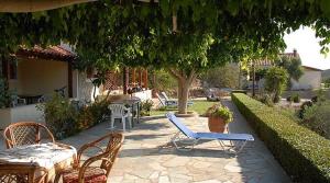 un patio con sillas, mesas y un árbol en Villa Amalia, en Palaikastro